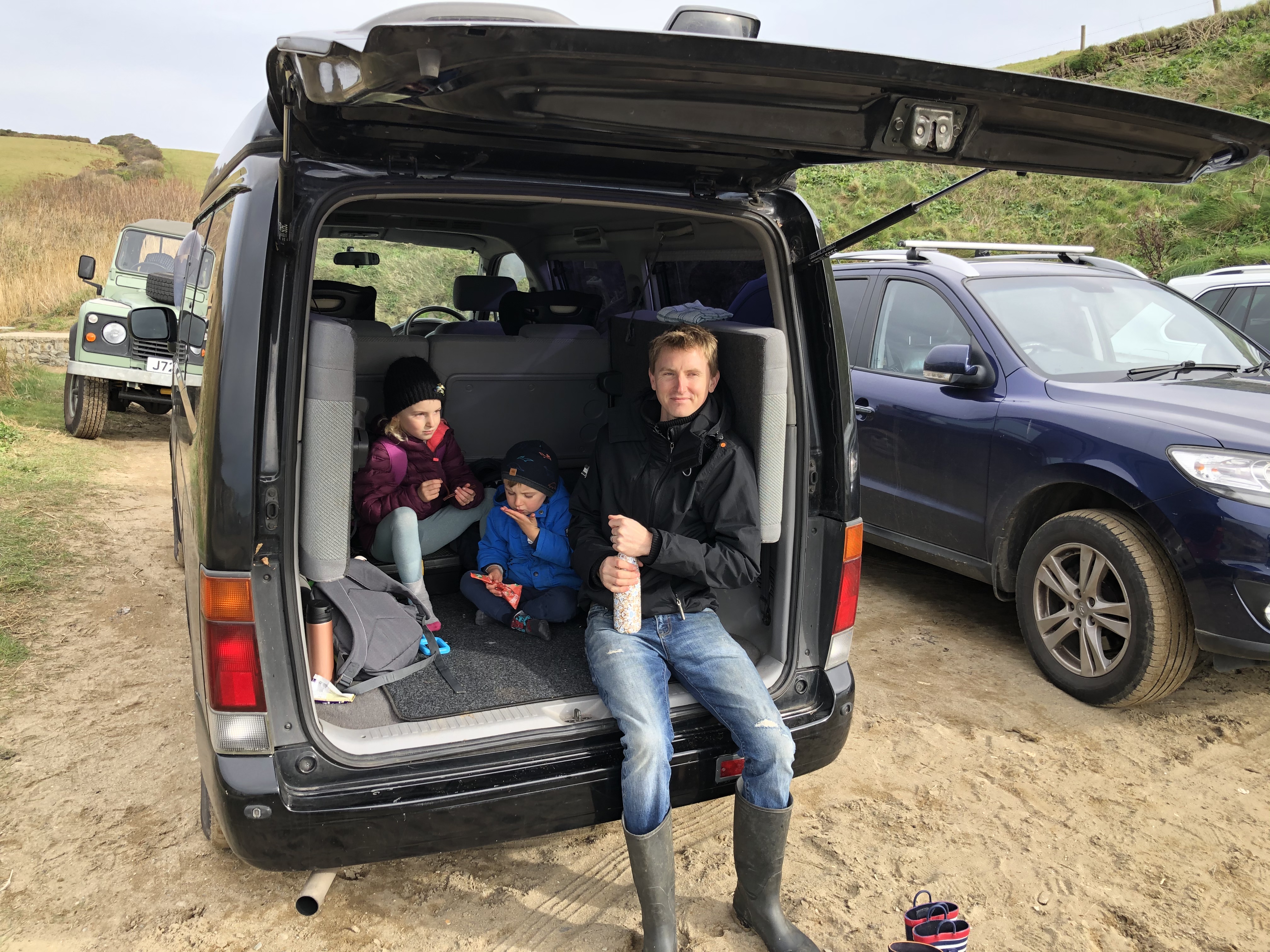 Cornwall with kids: Hemmick Beach - Ben and kids eating snacks in boot of Mazda Bongo