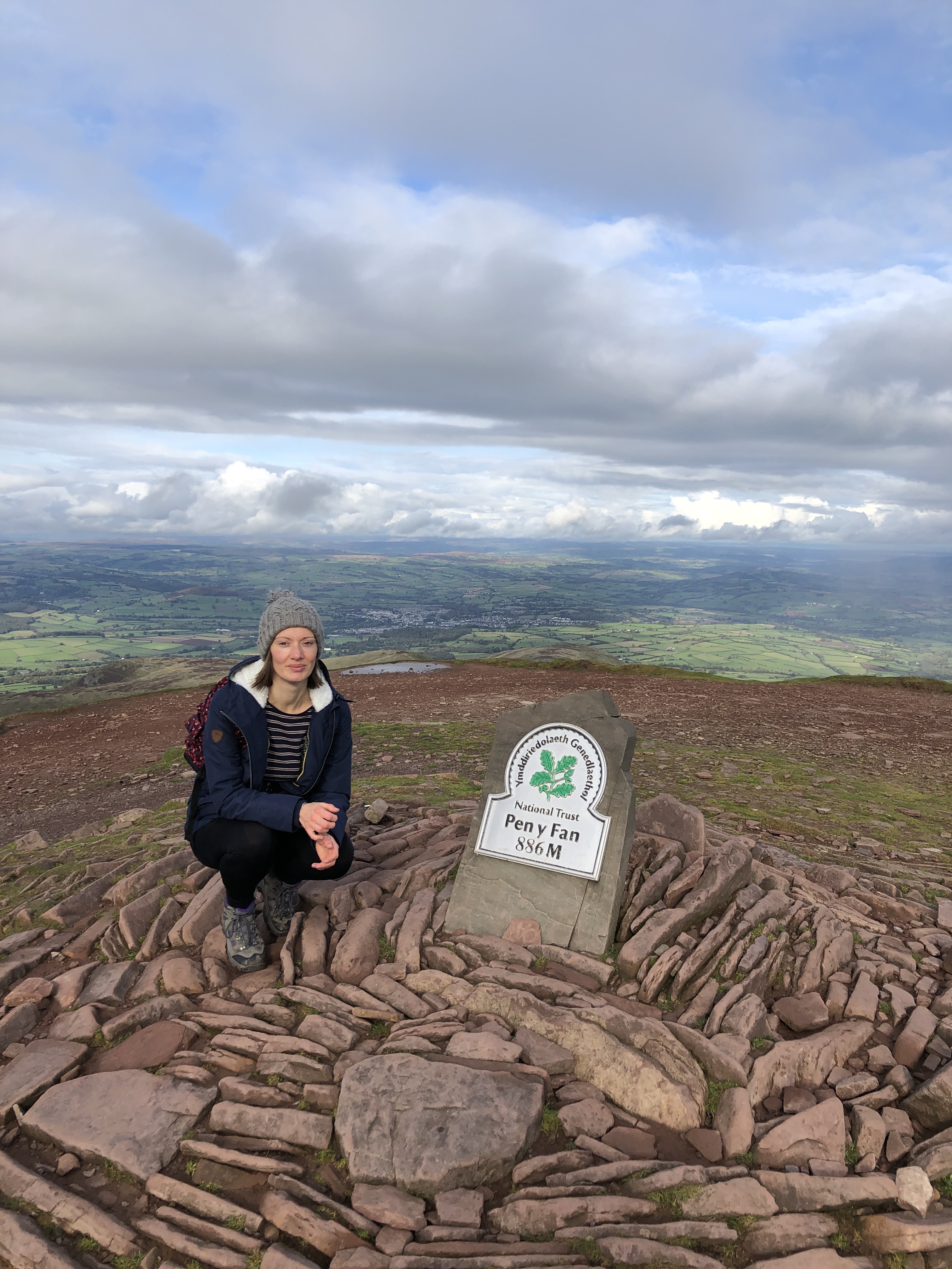 female hiker victoria sully next to Pen Y Fan summit peak 886m marker