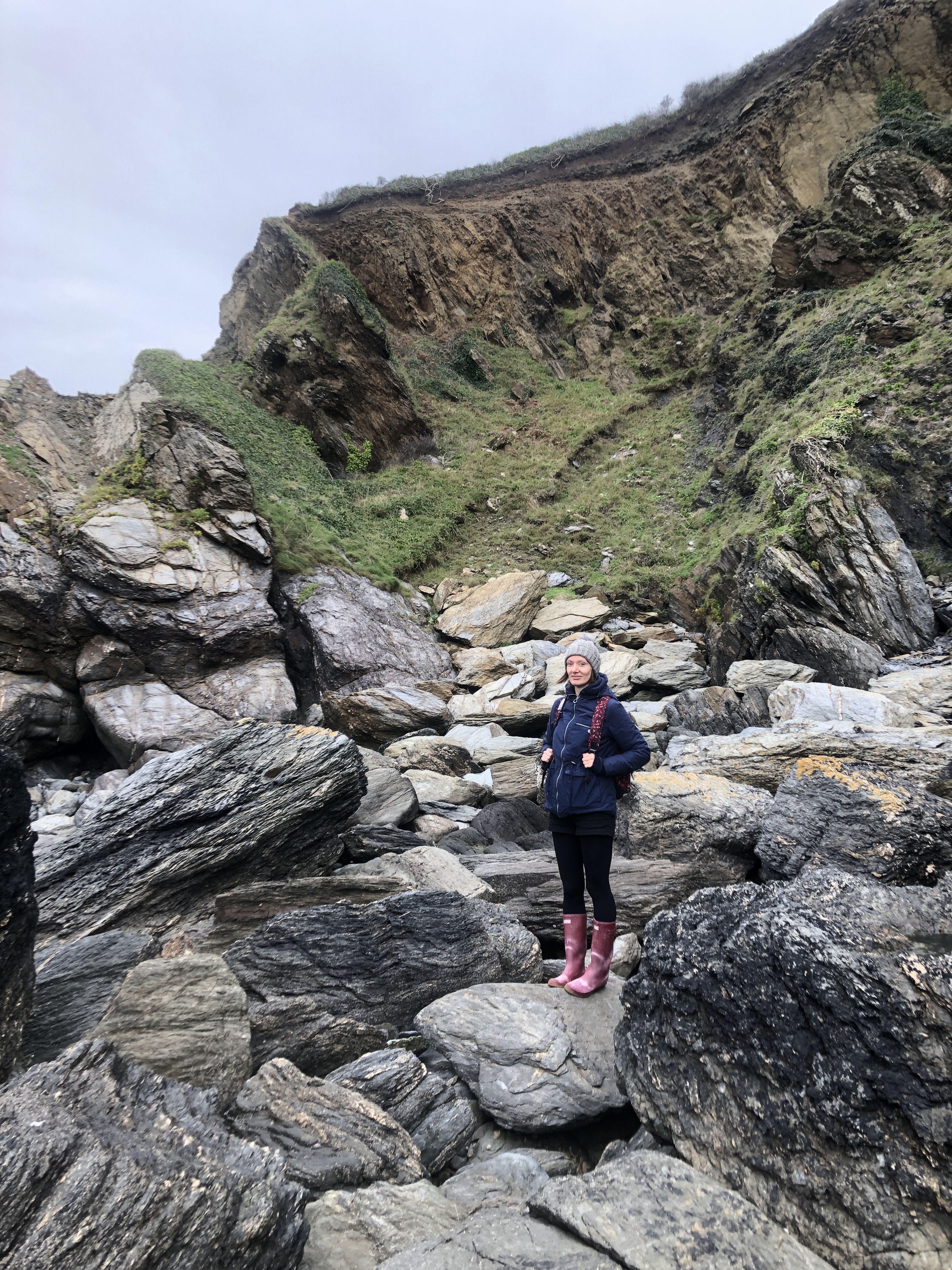 Cornwall with kids: Hemmick Beach - victoria standing on huge rocks by a cliff