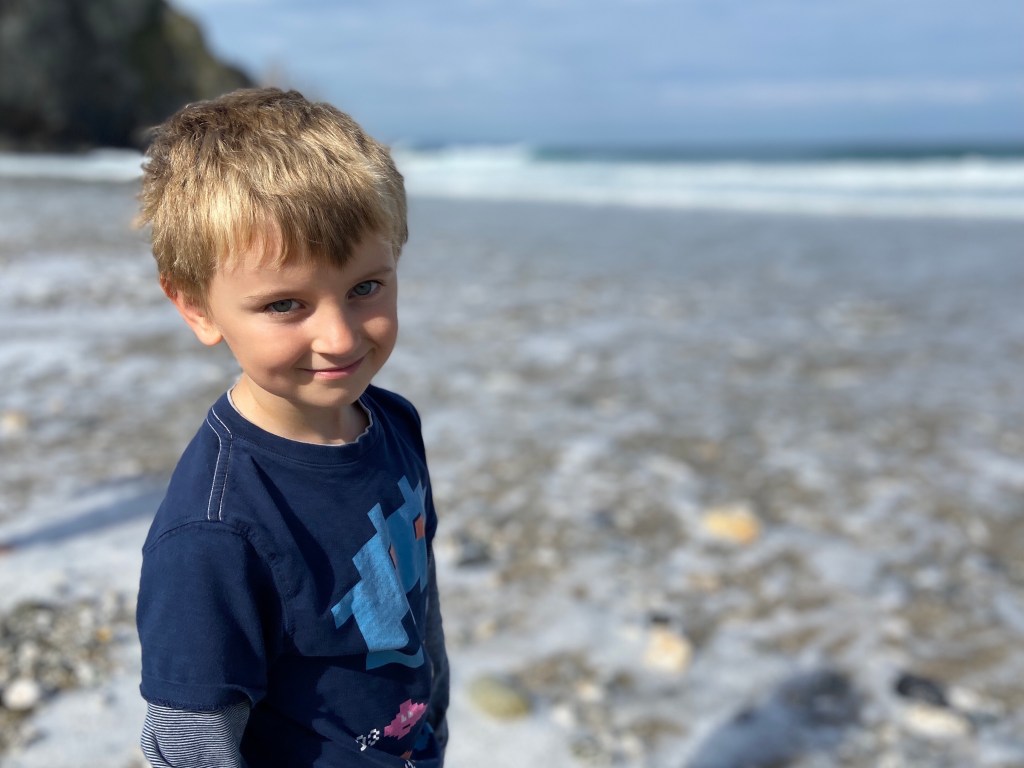 My 6 year old son smiling for a portrait photo at Porthtowan beach in Cornwall