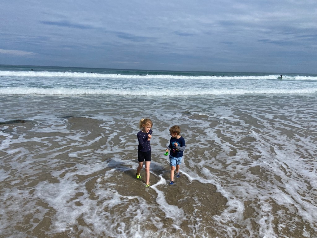 my two children running away from the sea in the shallow water playing at Porthtowan beach in Cornwall