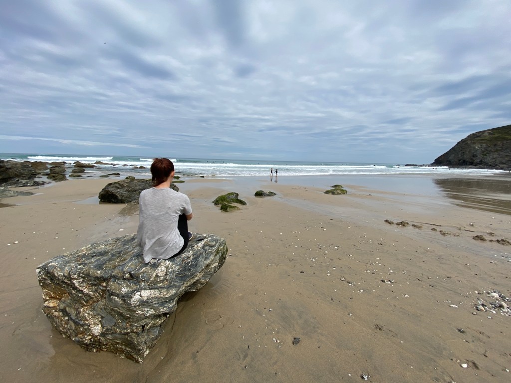 Me sat on a rock looking out to sea and watching my children splash in the sea at Porthtowan beach in Cornwall
