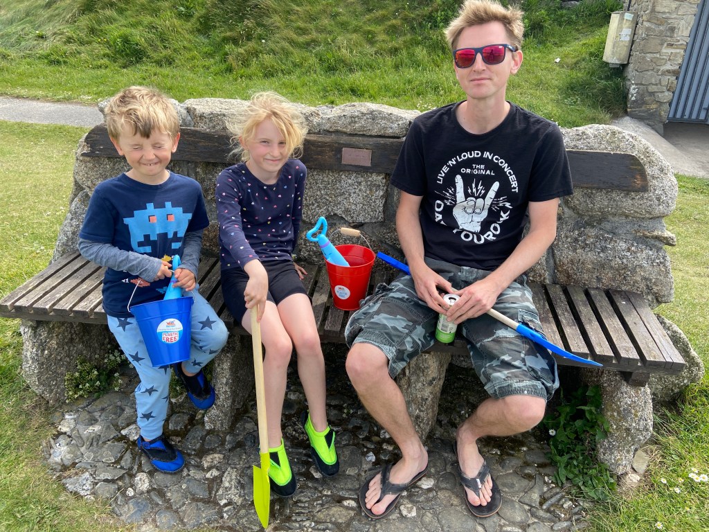 My husband and kids sat on a bench Perranporth beach in Cornwall