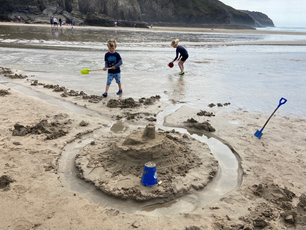 Kids playing in water and making sandcastles at Perranporth beach in Cornwall