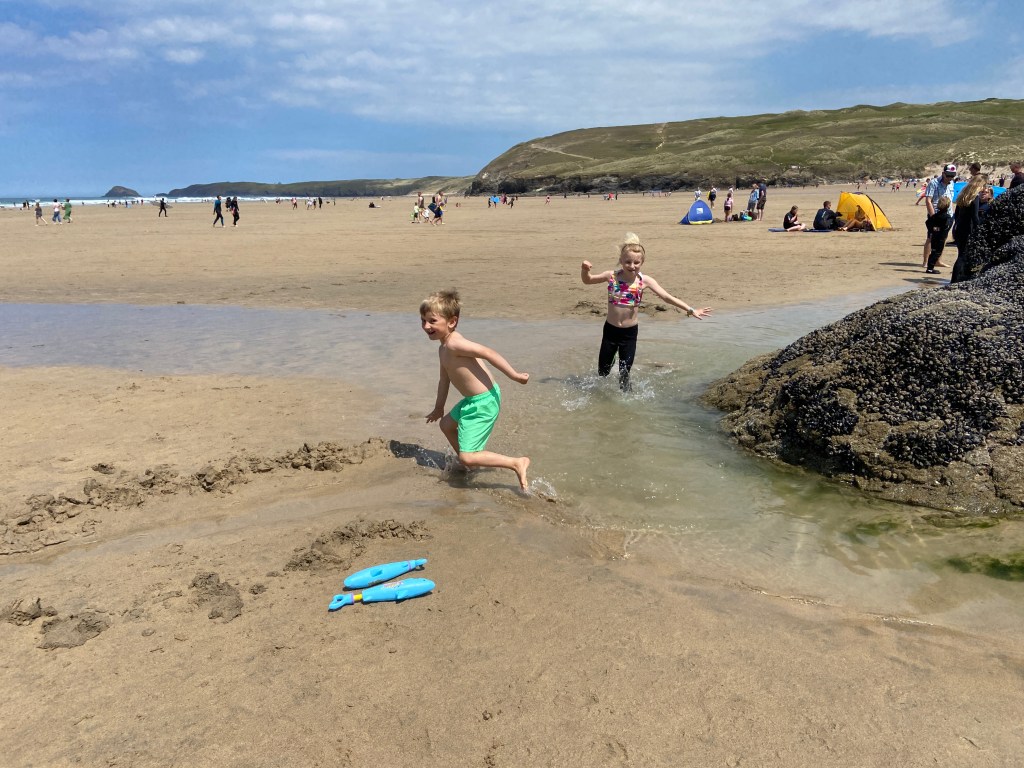 Kids splashing in the pools of water on the beach at Perranporth beach in Cornwall