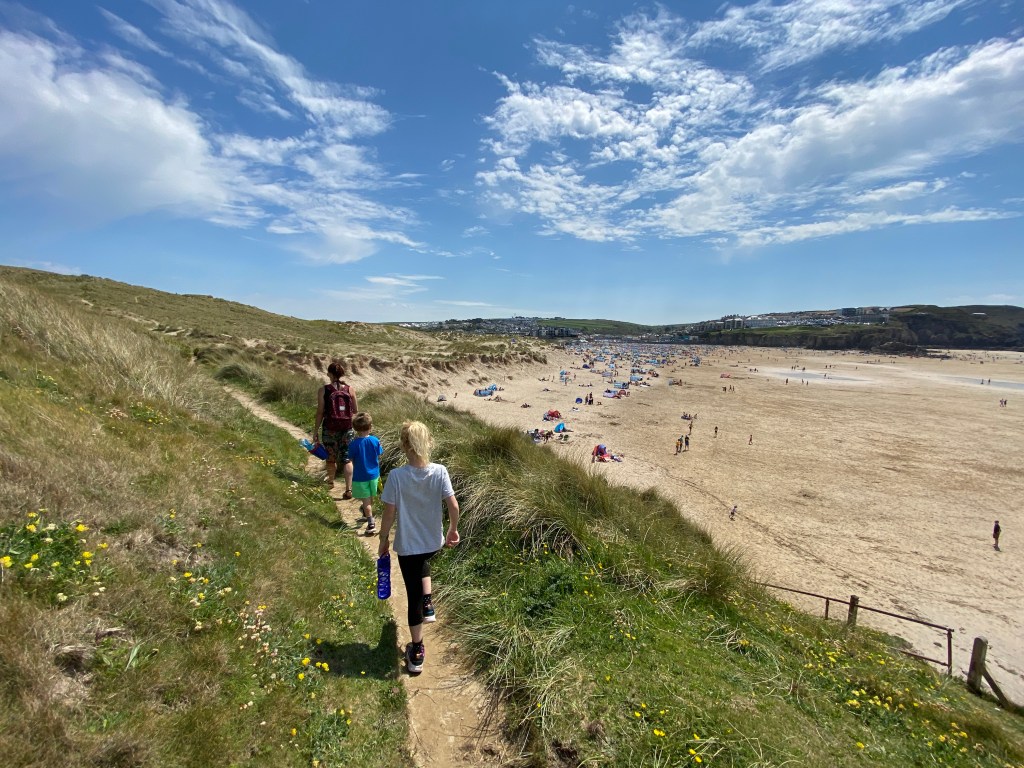 Family walking along the sand dunes at Perranporth beach in Cornwall