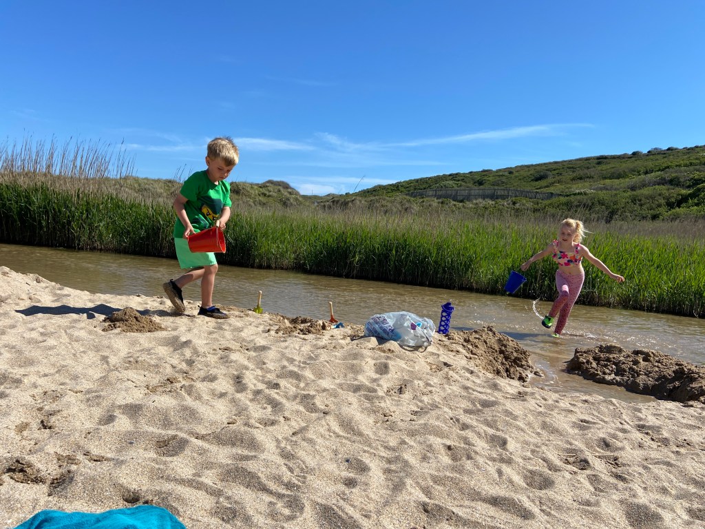 kids splashing in the river at Holywell beach near newquay cornwall