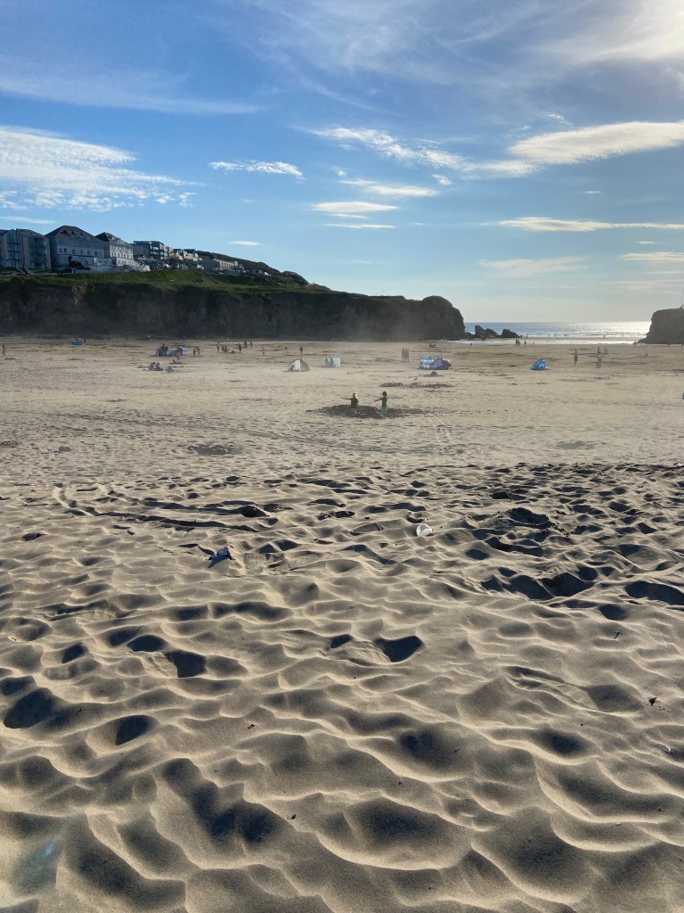 Kids playing in giant hole in the sand at Perranporth beach in Cornwall