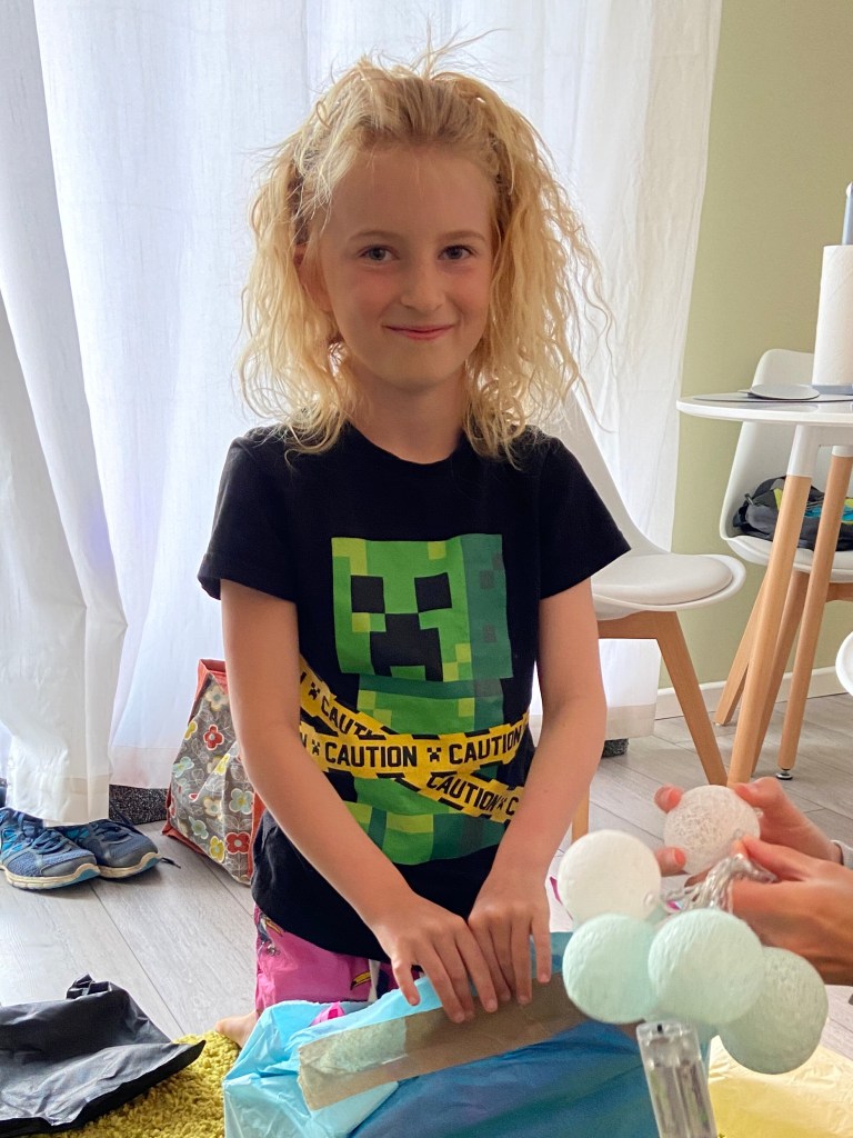 9 year old birthday girl opening presents with smile