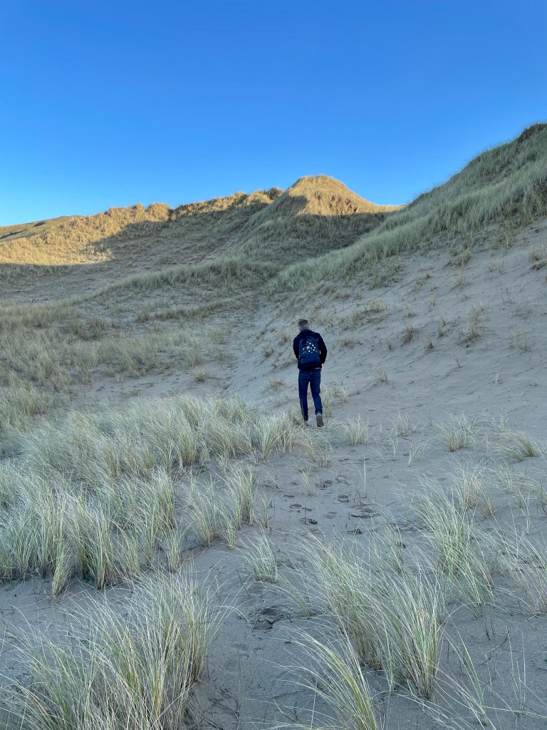 man walking up sand dunes perranporth cornwall