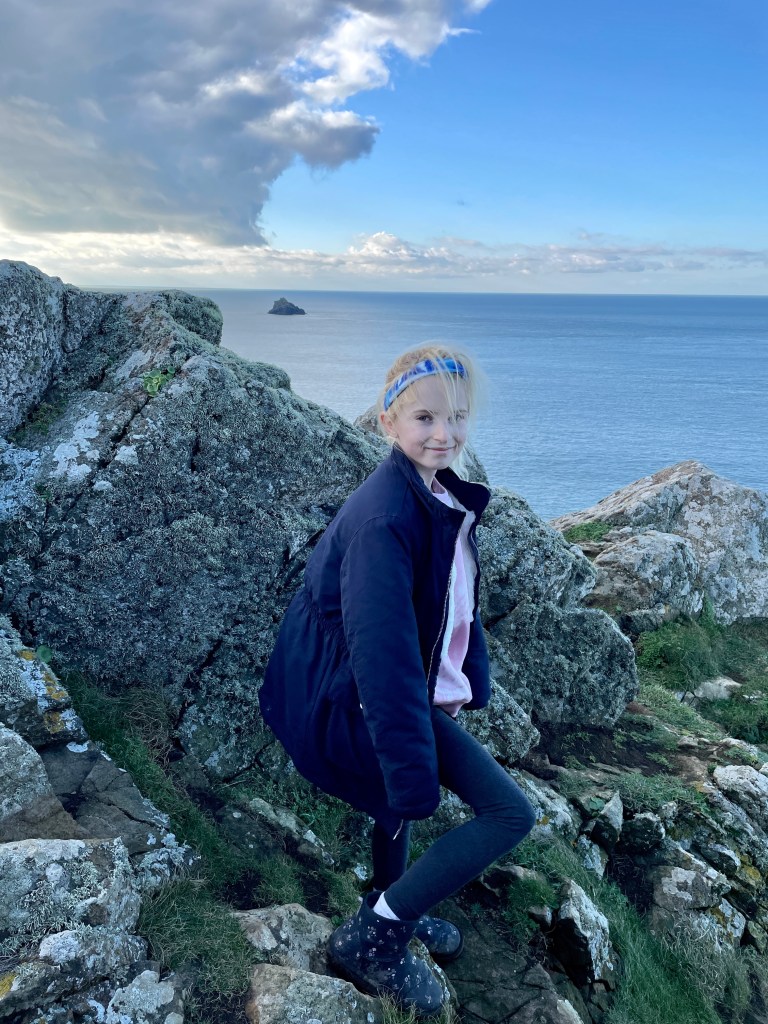 Climbing the rocks on the rumps headland Cornwall