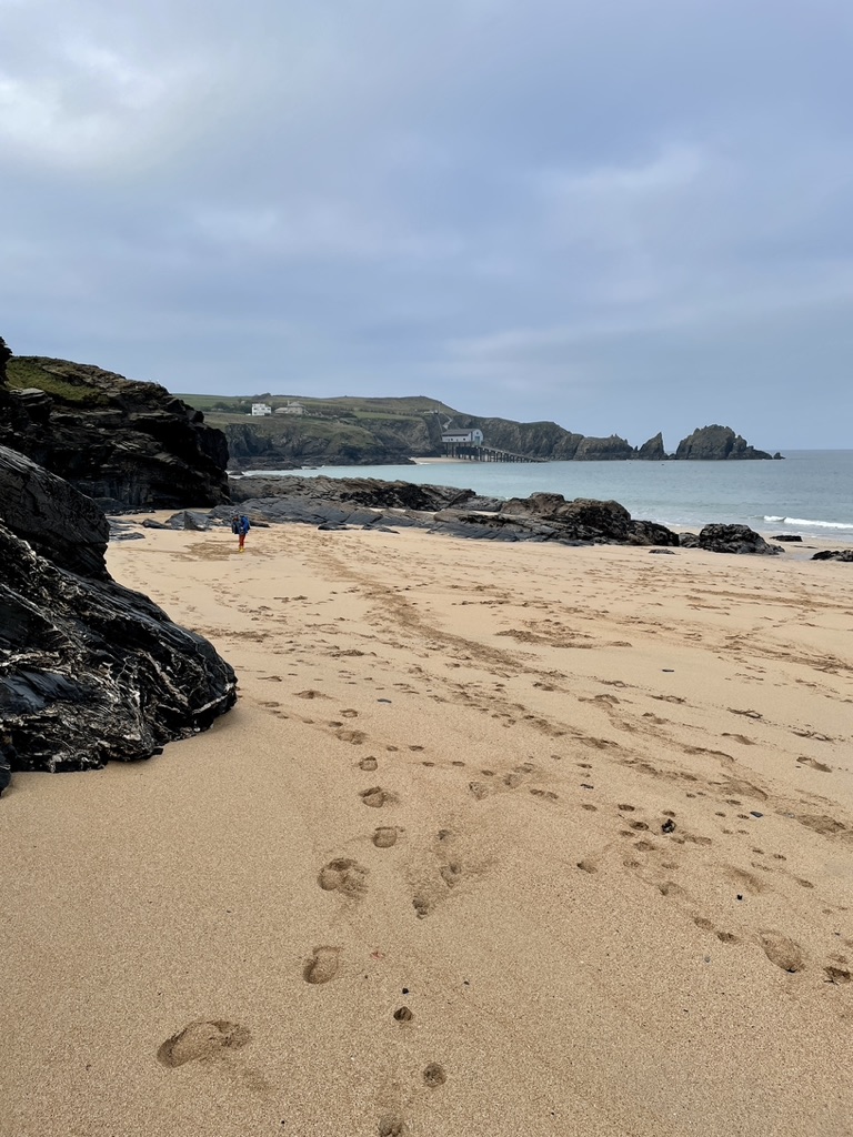 footprints in sand mother iveys bay cornwall padstow lifeboat station in distance