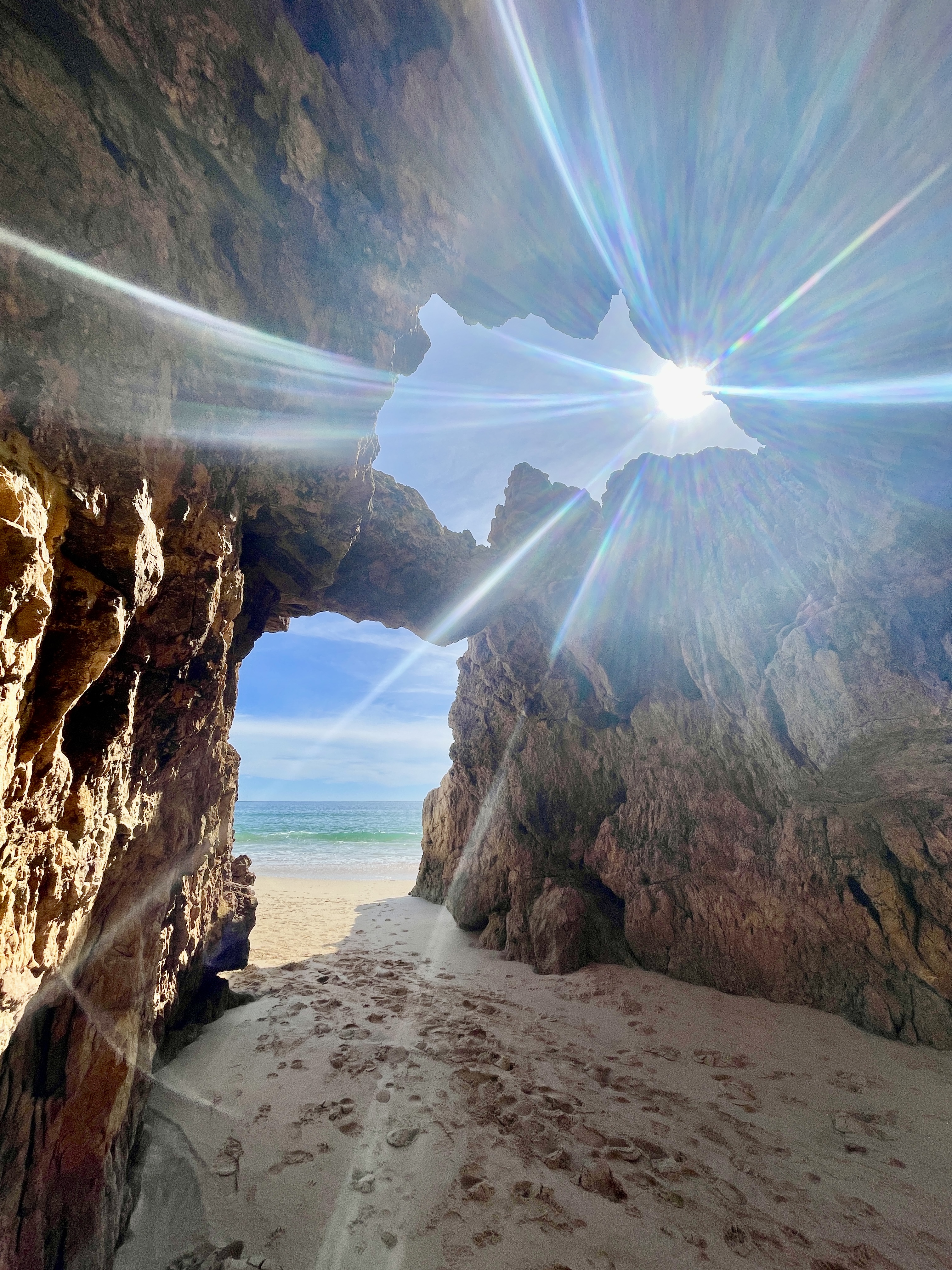 Unique rock formations with a large hole opening up to the sky at Praia da Andorinha