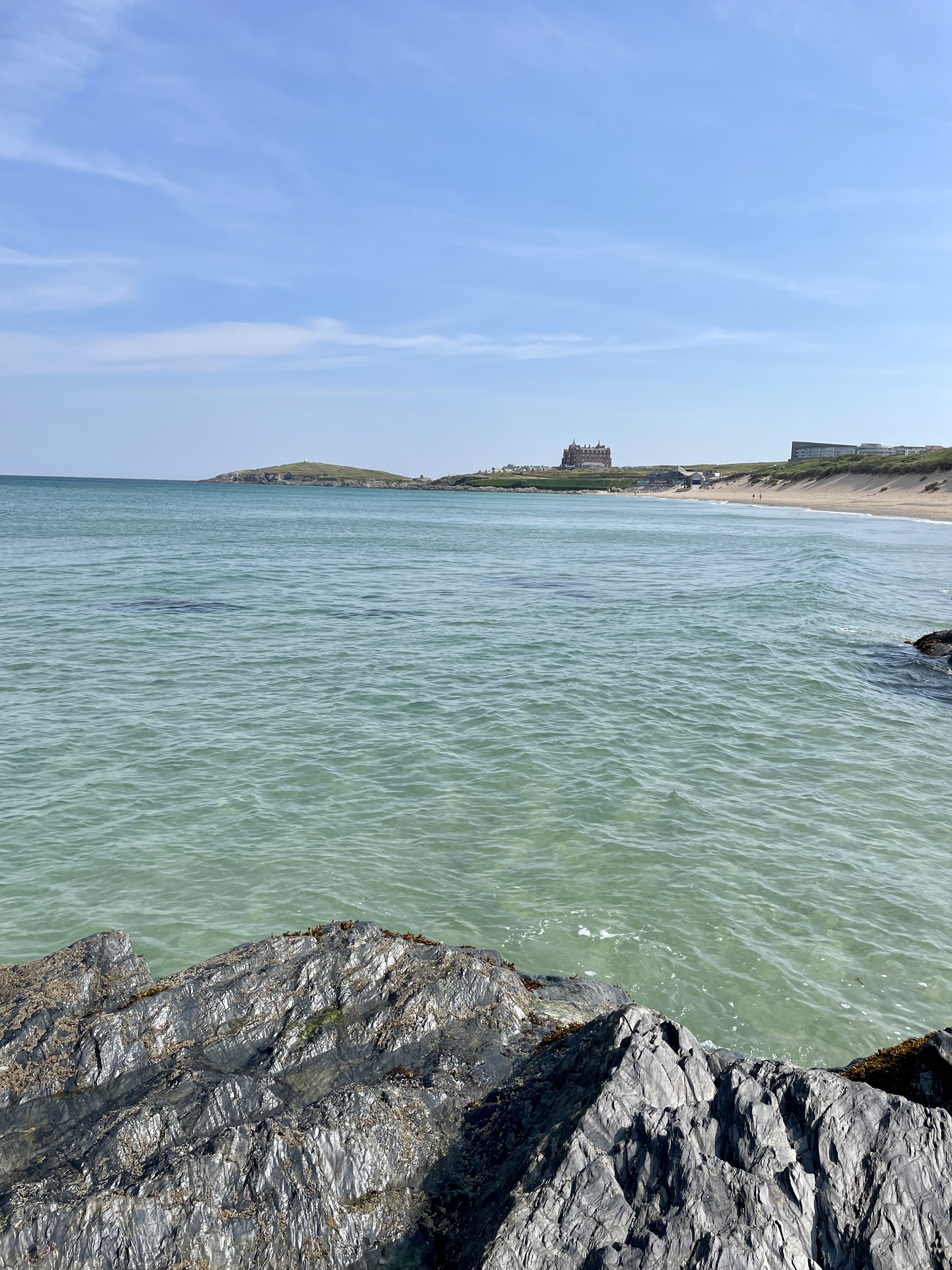 Beautiful clear waters at Fistral Beach in Newquay Cornwall with iconic Headland Hotel in the background and Towan headland.
