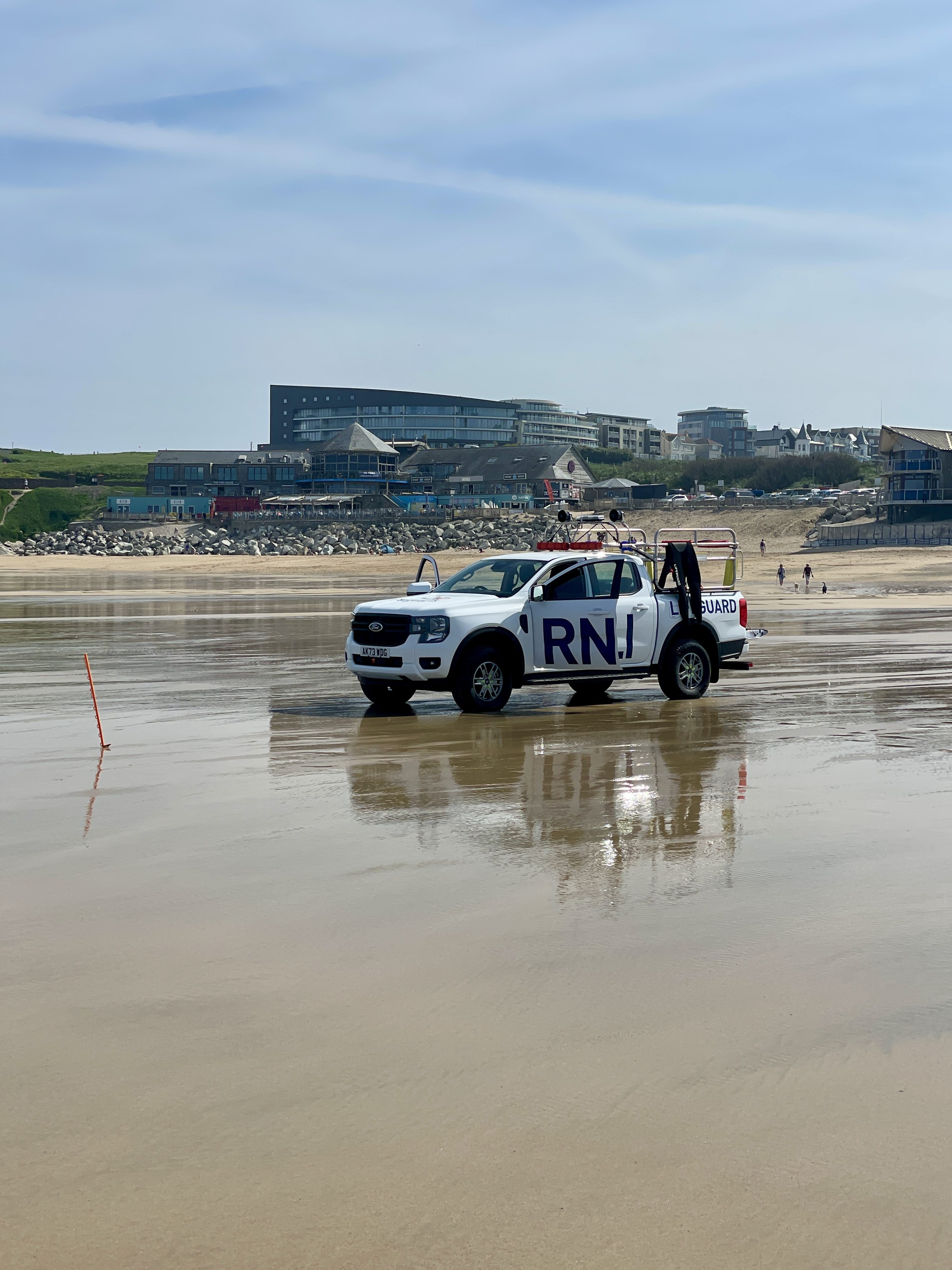 RNLI on Fistral Beach in May with Fistral Beach Complex in the Background