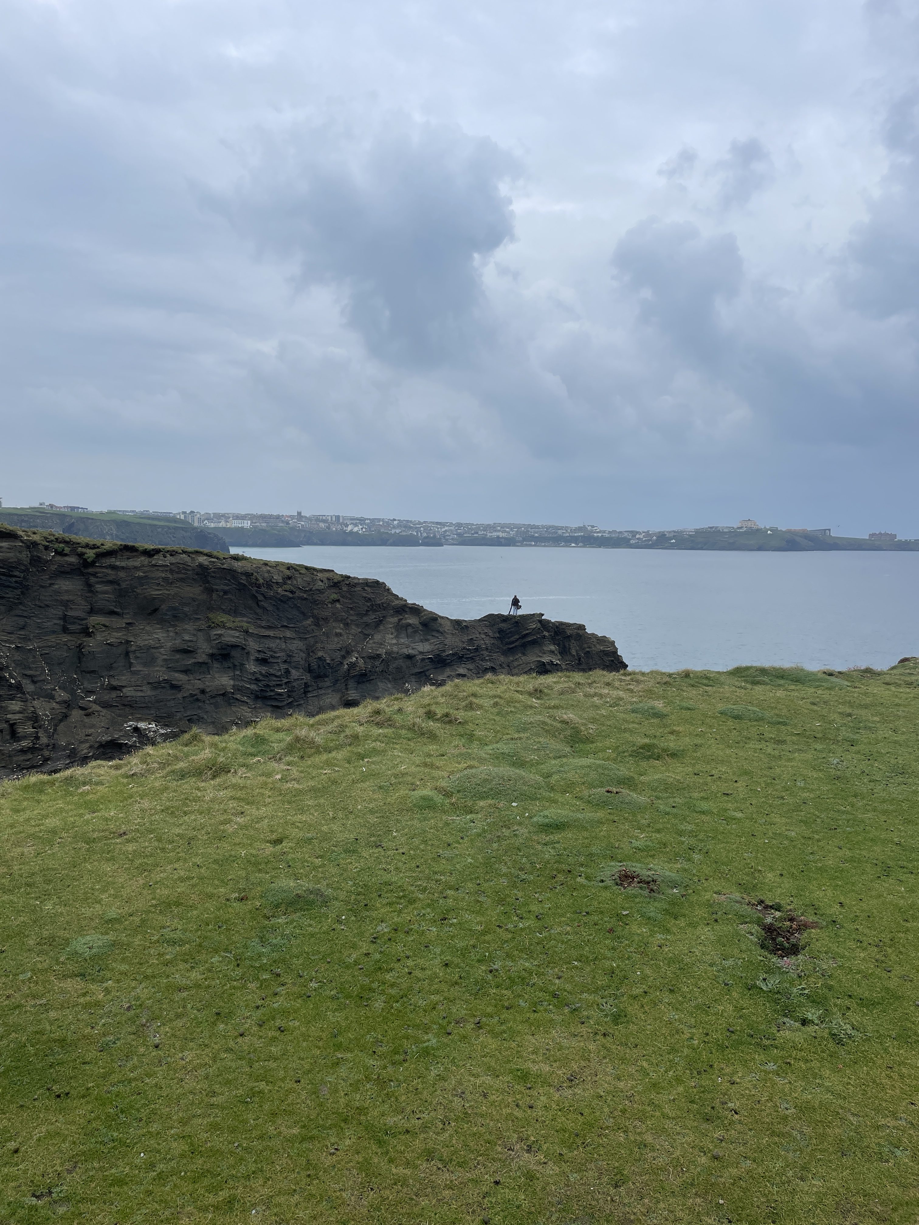 Fisherman at Trevelgue Head in Porth on a cloudy day