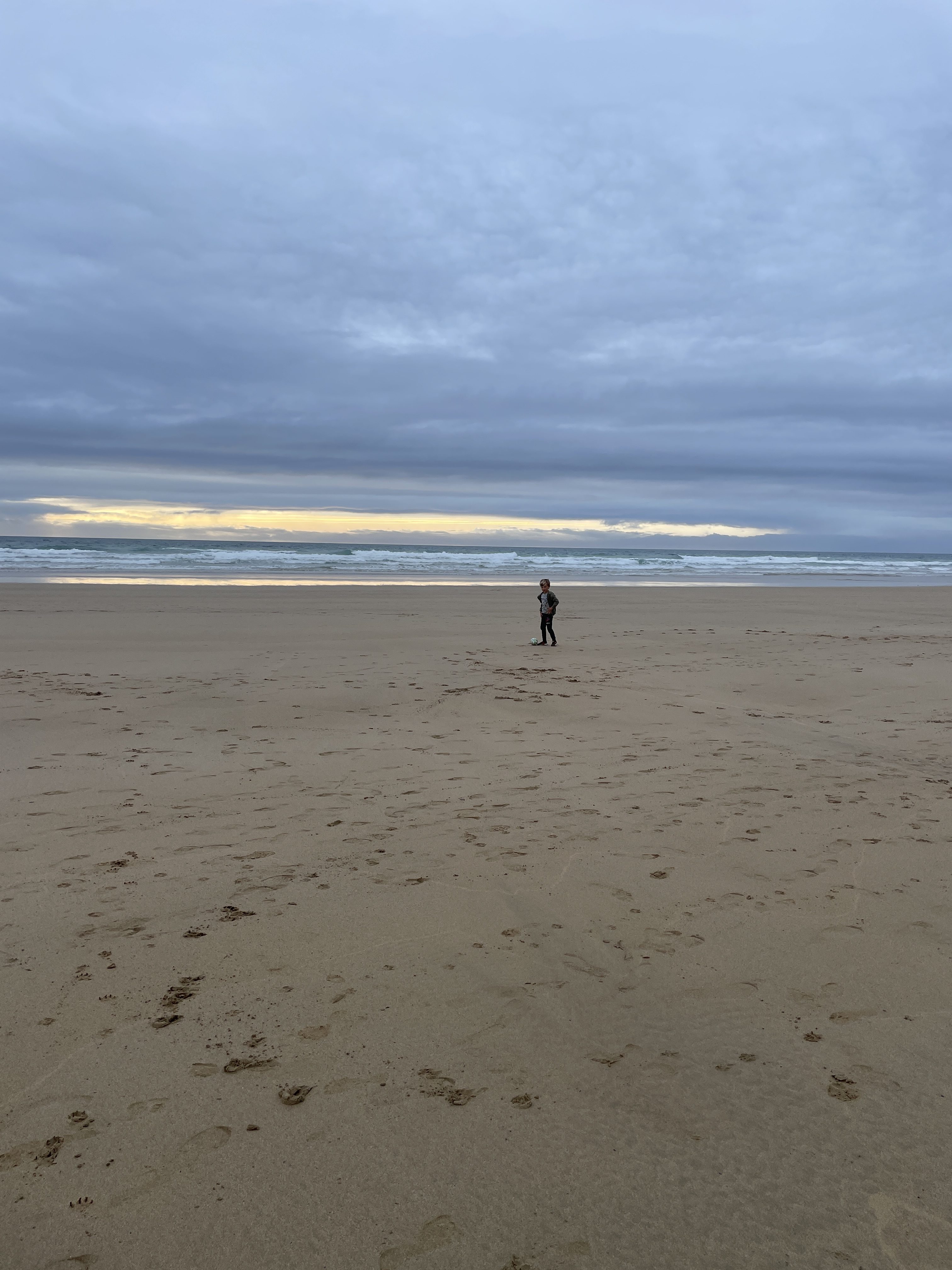 Watergate Bay child playing with ball on the beach at dusk