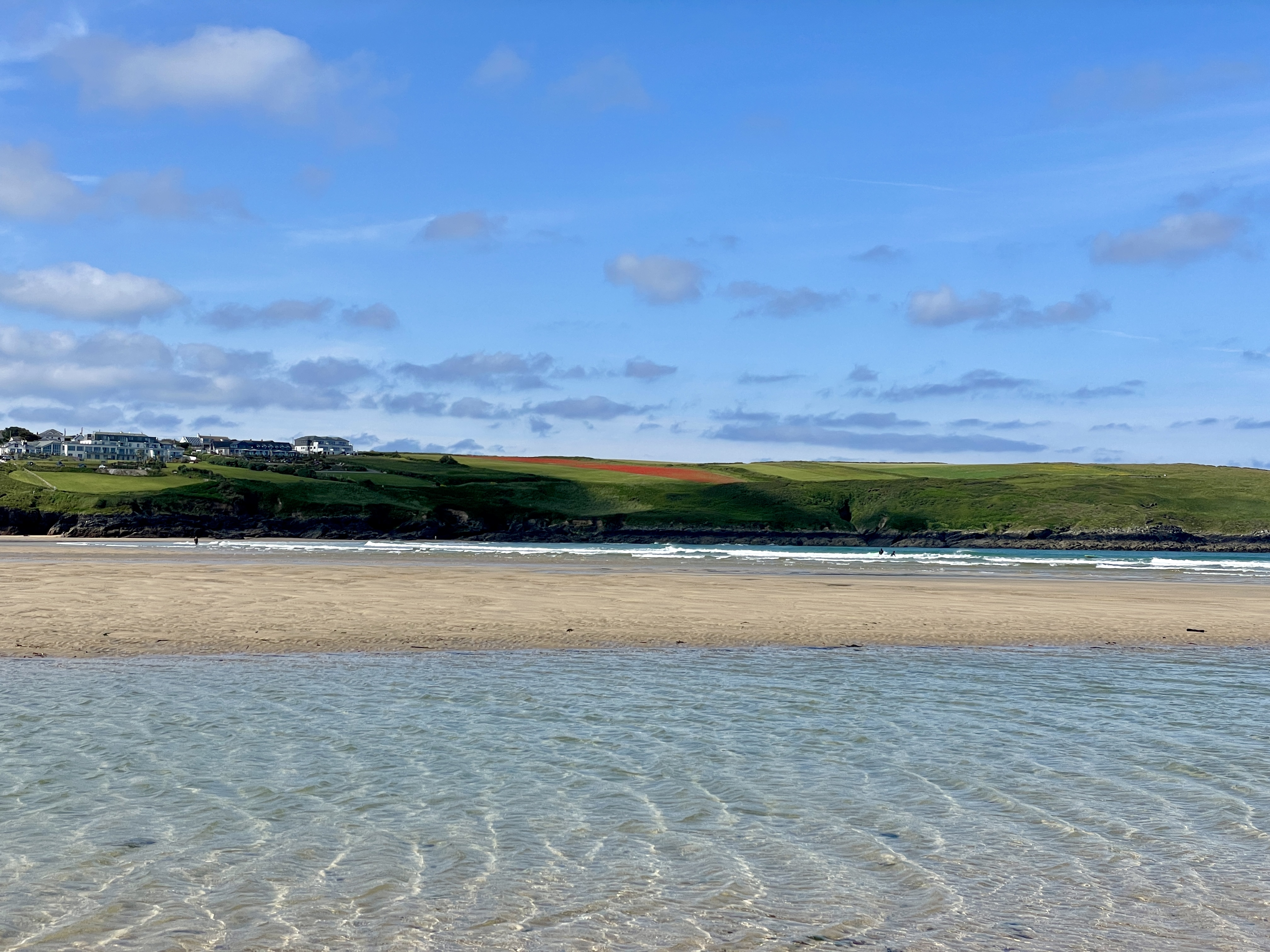 View of Polly Joke poppy fields from West Pentire in Newquay looking across the clear waters and sand of Crantock Beach