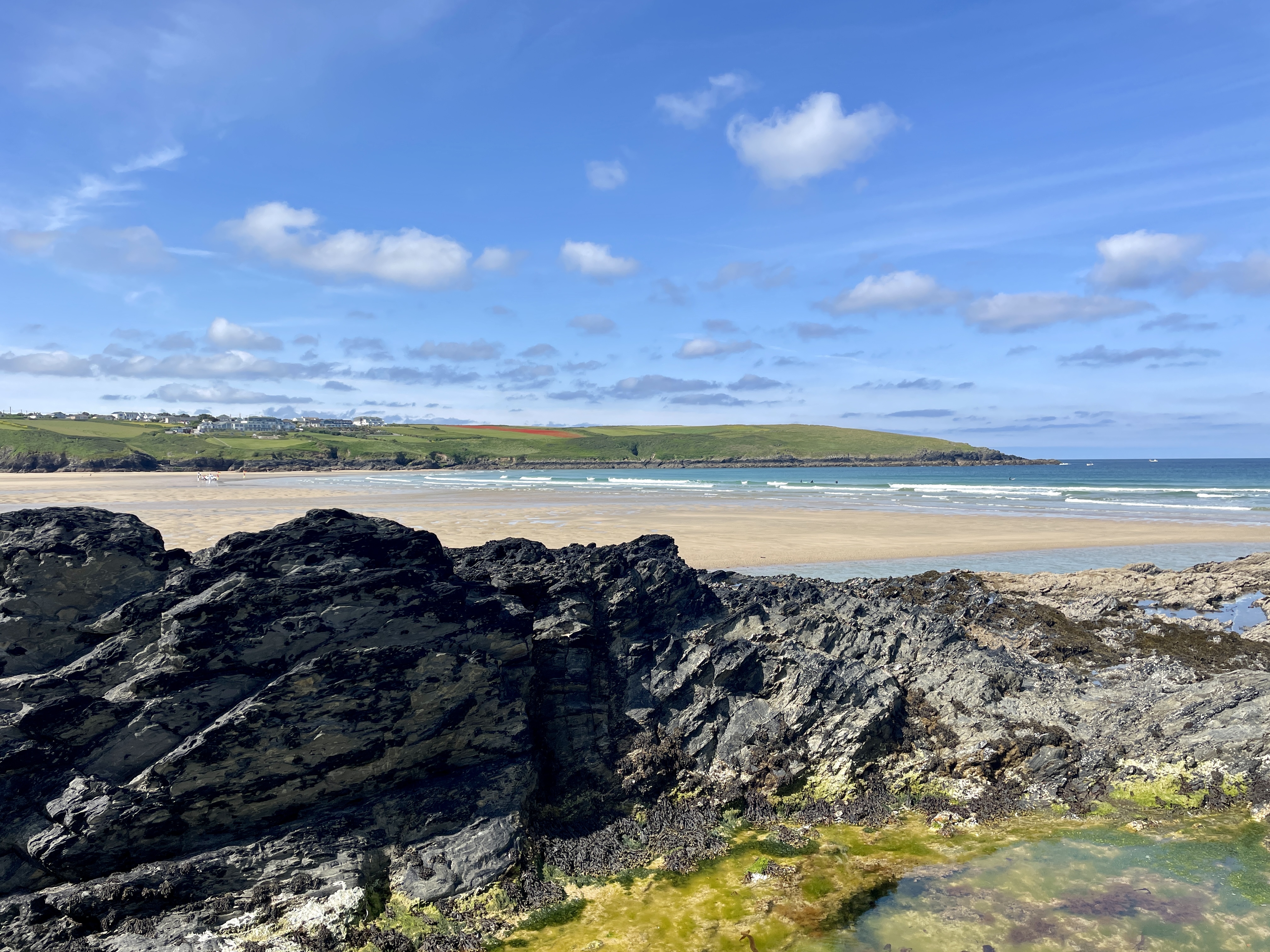 Views of Polly Joke poppy fields from West Pentire in Newquay looking across the clear waters and sand of Crantock Beach