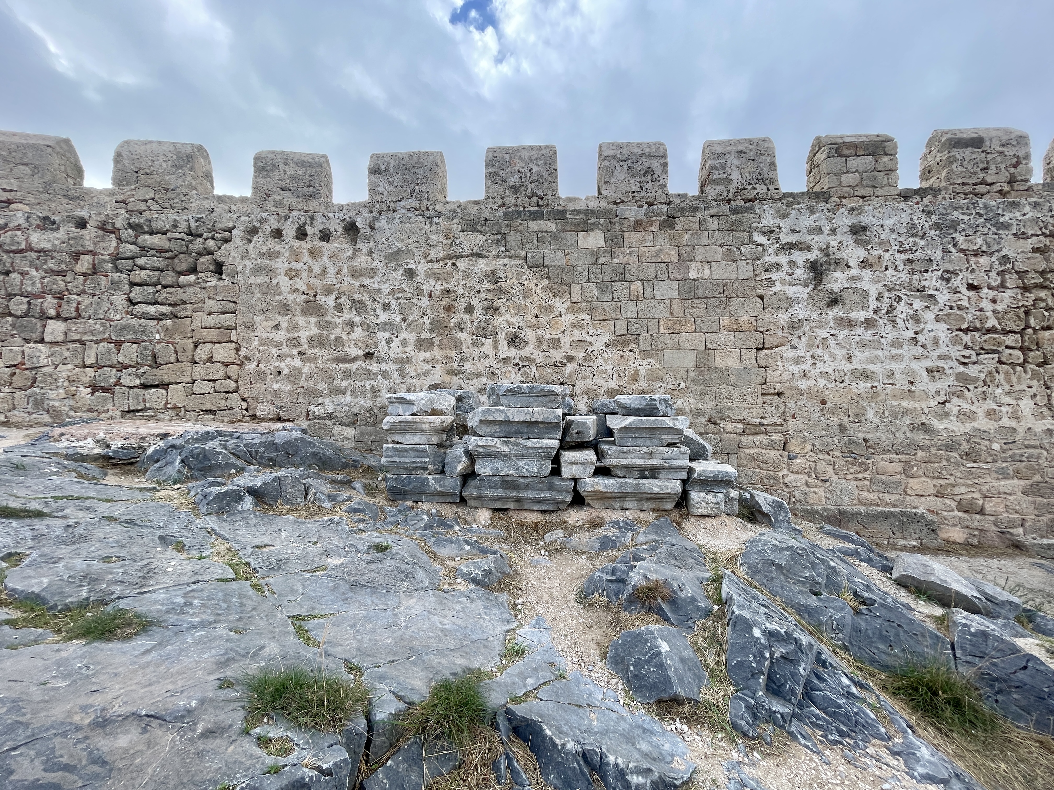 Salvaged architectural pieces are neatly stacked around the Lindos Acropolis site