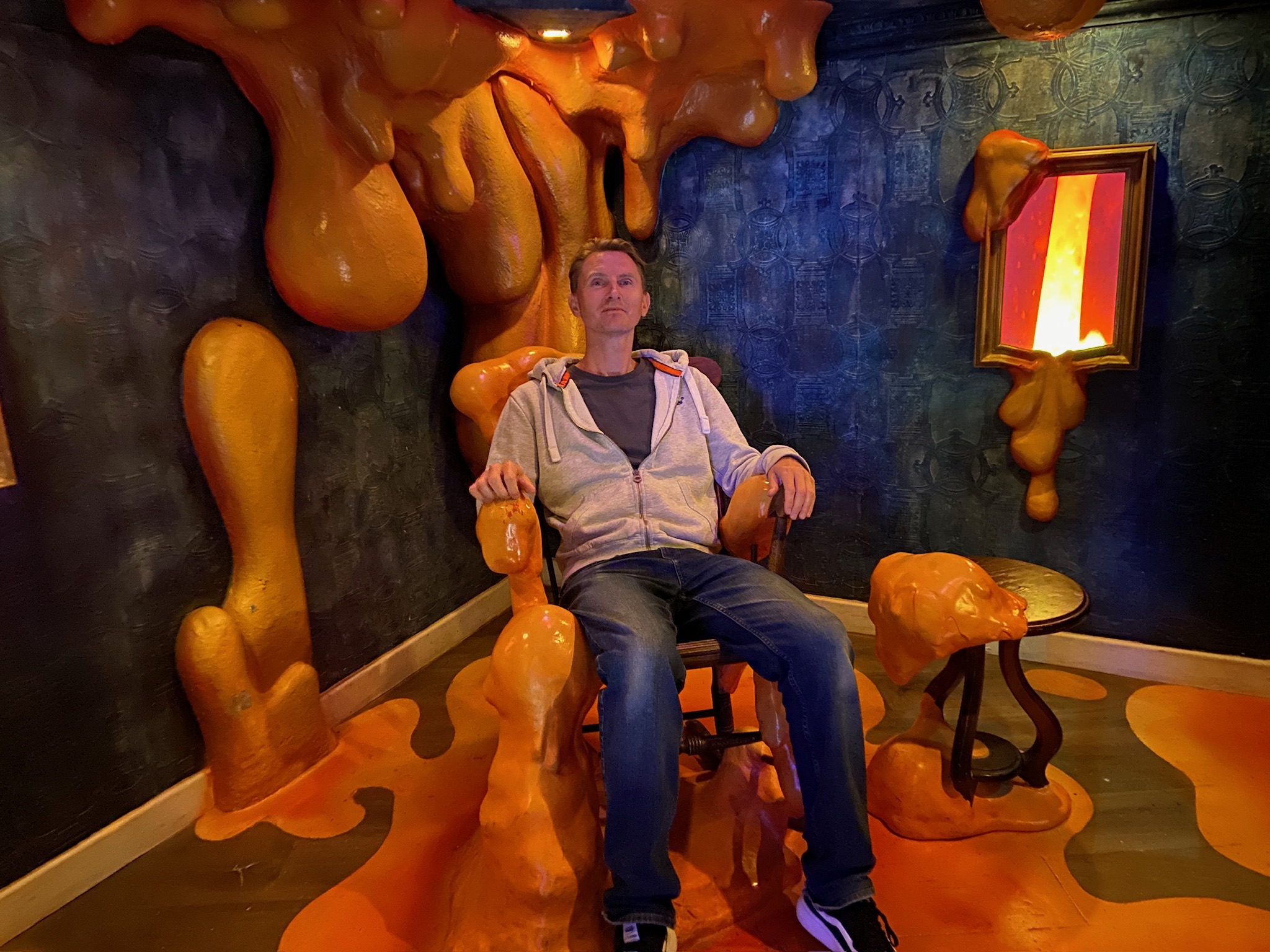 Man sitting in a chair surrounded by orange goo dripping from walls at Wake the Tiger Bristol