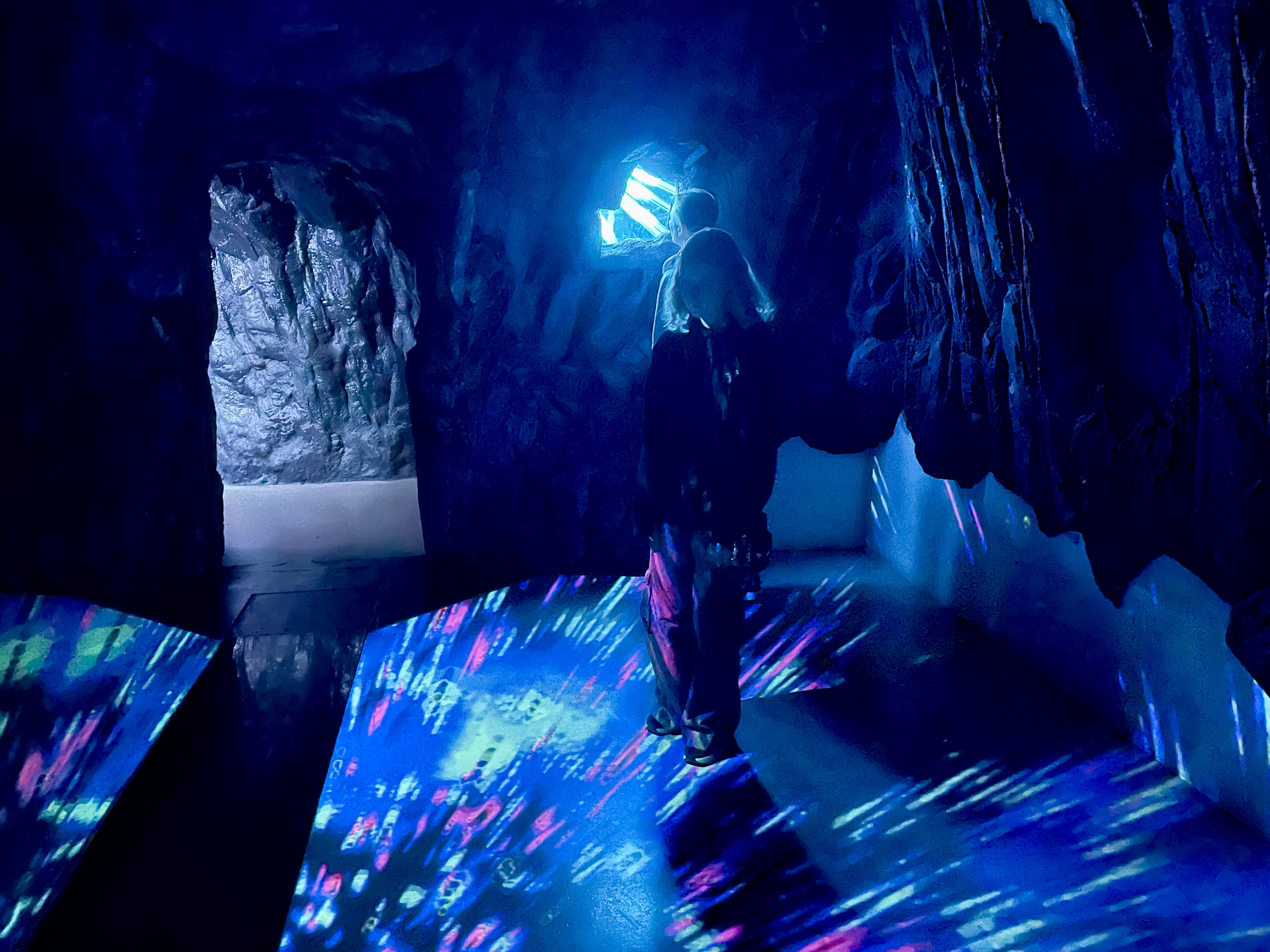 Visitor exploring cave room with light up projected floor at Wake the Tiger Bristol
