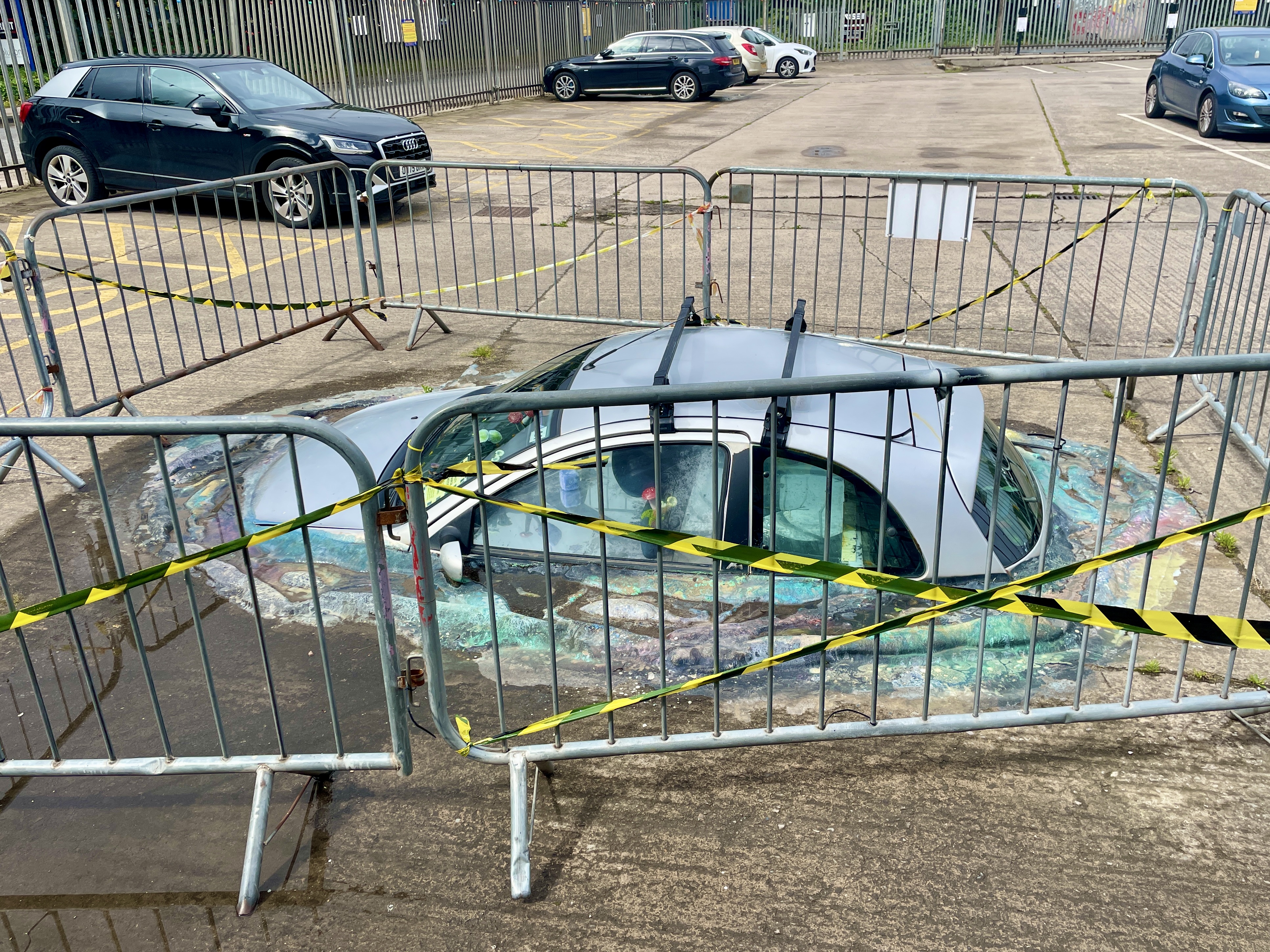 Wake the Tiger Bristol car installation sinking into the ground surrounded by barriers and hazard tape