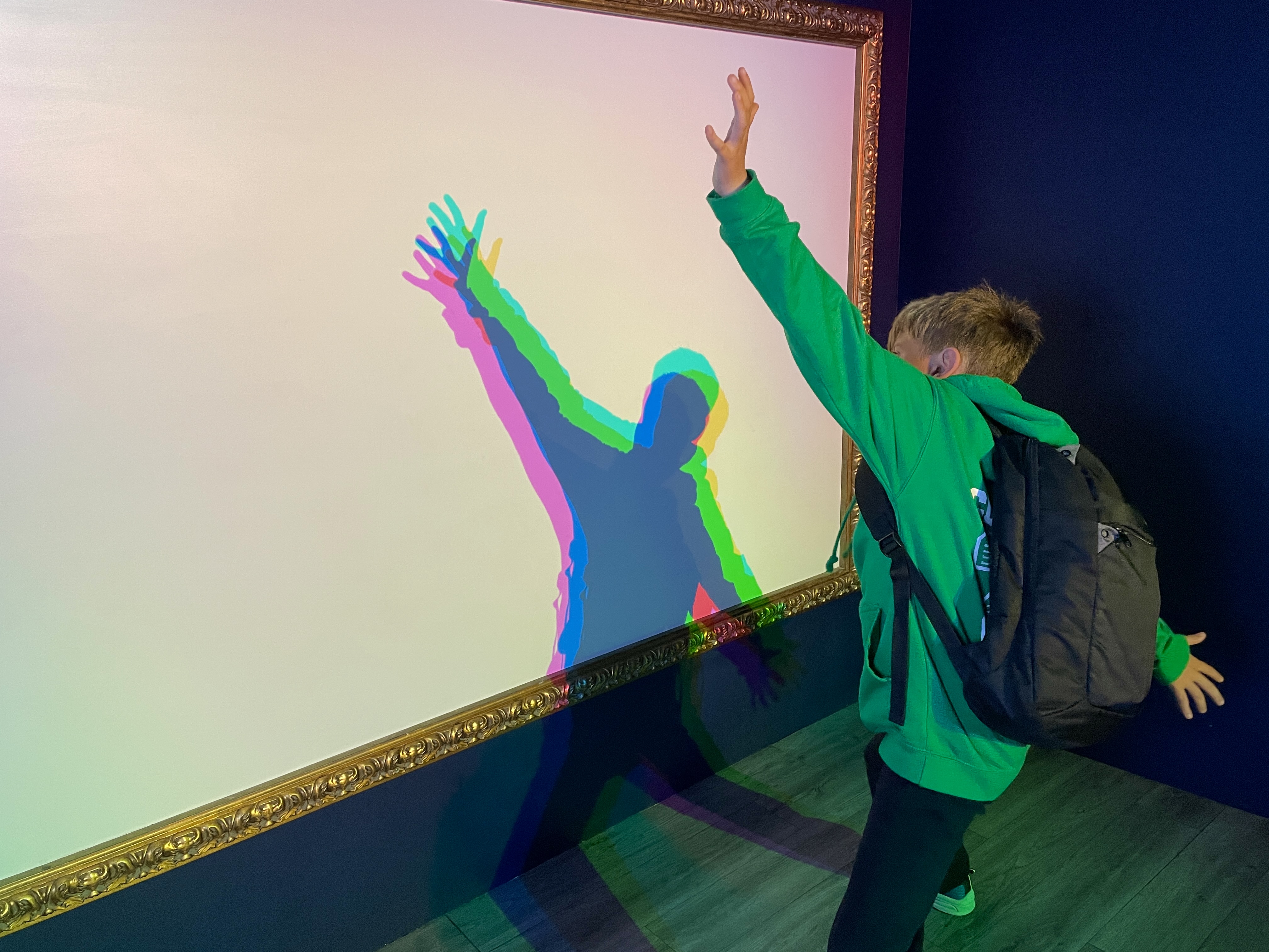 Child posing at the multicoloured silhouette shadow screen at We The Curious Bristol