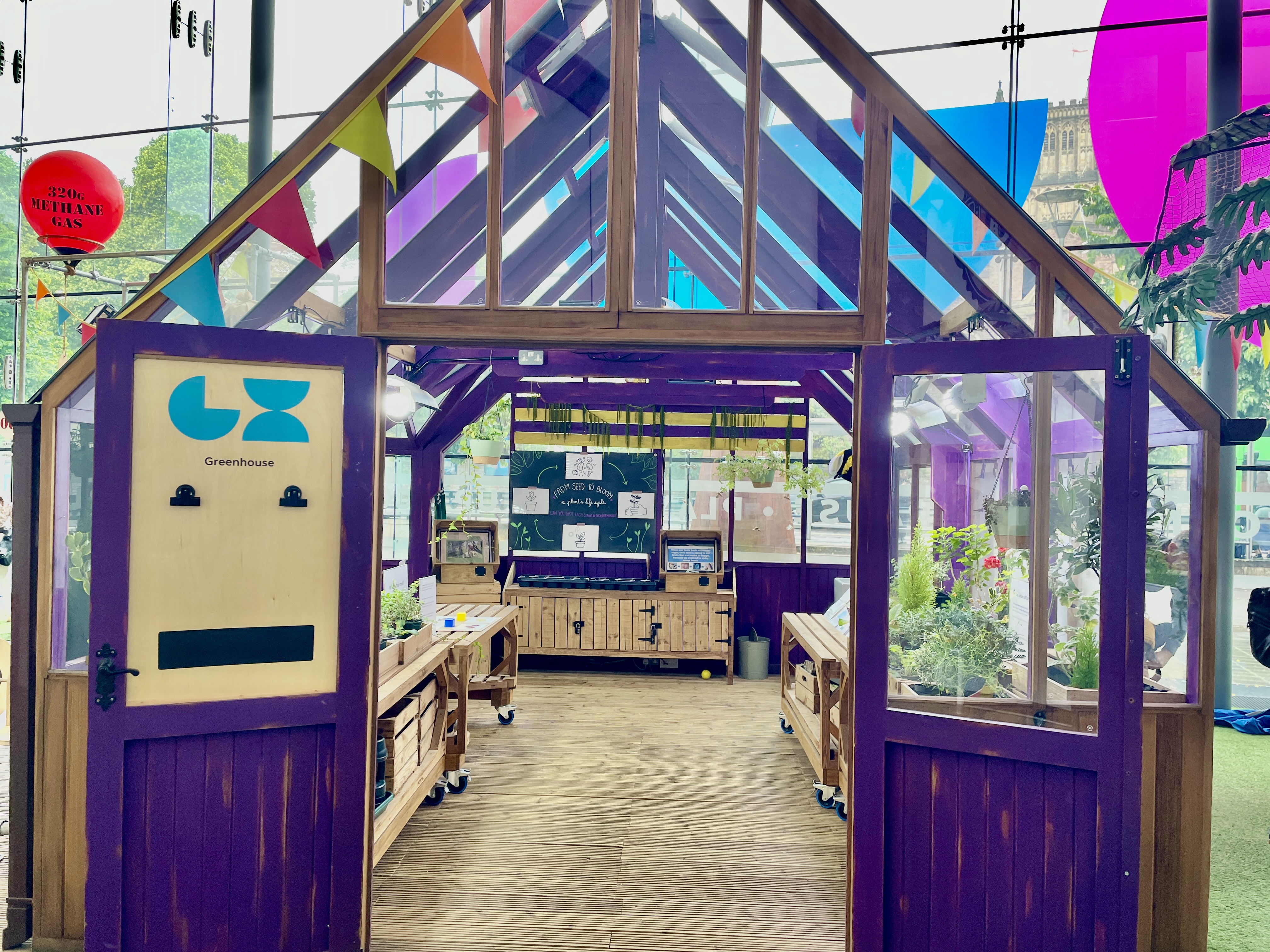 The Greenhouse exhibit at We The Curious Bristol with purple wooden frame and plants inside